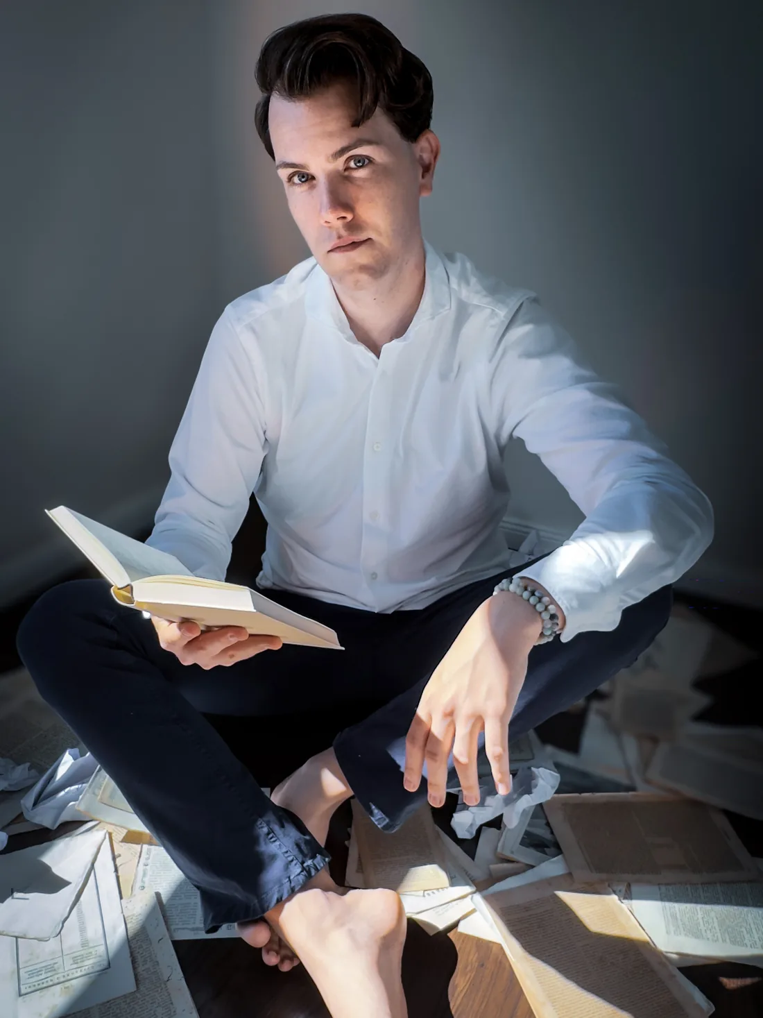 Mika sitzt am Boden zwischen aufgeschlagenen Büchern und Notizen